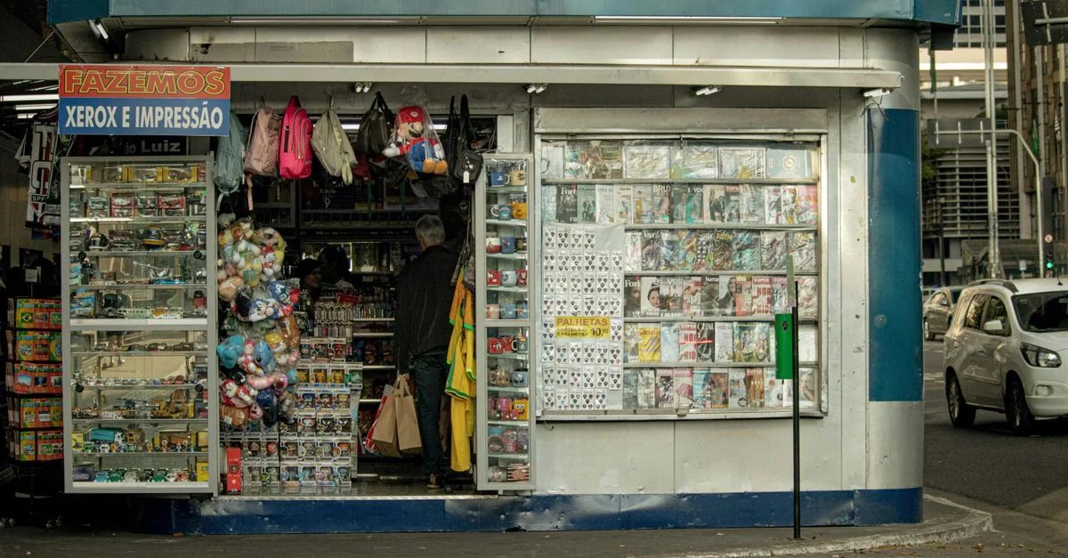 Kiosque vivant affichant des magazines et des jouets dans une rue animée.