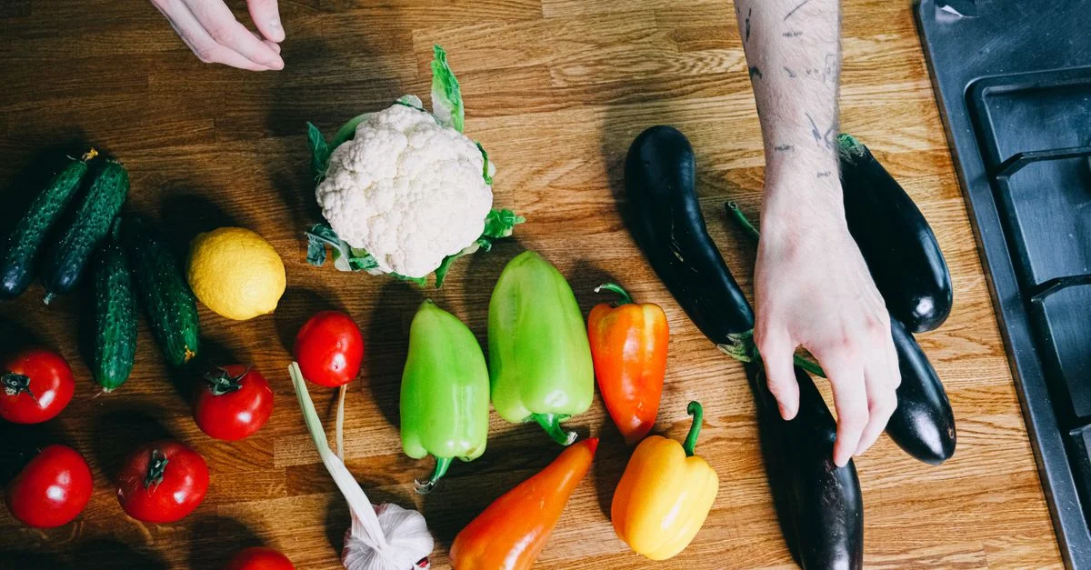 Des légumes colorés, y compris des poivrons, des tomates et des aubergines, disposés sur un plan de travail de cuisine.
